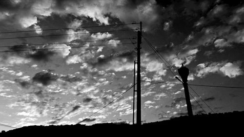 Low angle view of power lines against cloudy sky