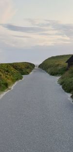 Empty road along landscape against sky