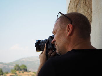 Portrait of man photographing against sky