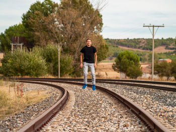 Man standing on railroad track against sky