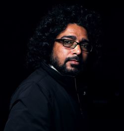 Portrait of man wearing eyeglasses against black background