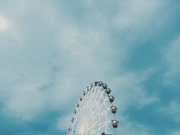 Low angle view of ferris wheel against cloudy sky