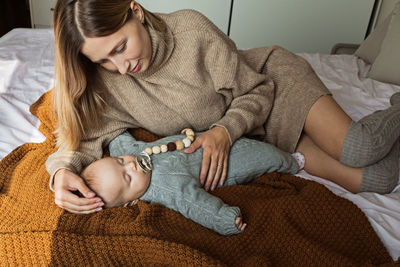 Mother with baby lying down on bed at home