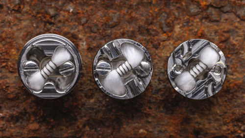 Single space coil in high end rebuildable dripping atomizers on rusty texture background, top view