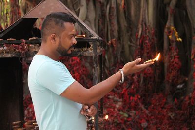 Side view of shirtless man holding burning at temple