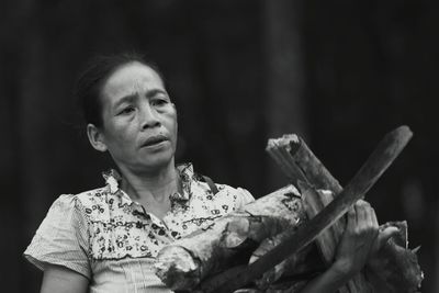 Close-up of mature woman carrying firewood