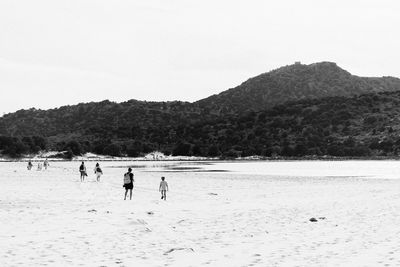 People at beach against clear sky