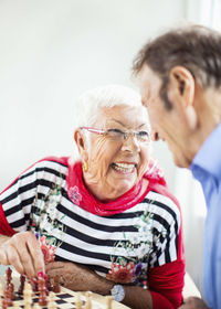 Happy senior couple looking at each other while playing chess in nursing home