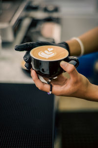 Cropped hand holding coffee at table