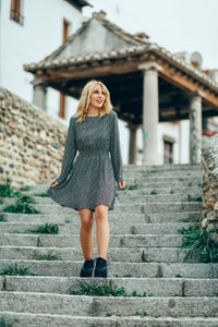 Low angle view of young woman looking away while standing on steps