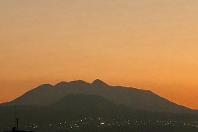 Scenic view of silhouette mountains against orange sky