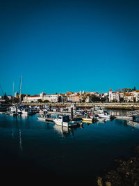 Sailboats moored in harbor against clear blue sky