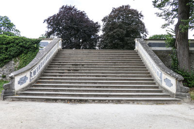 Low angle view of steps amidst trees against sky