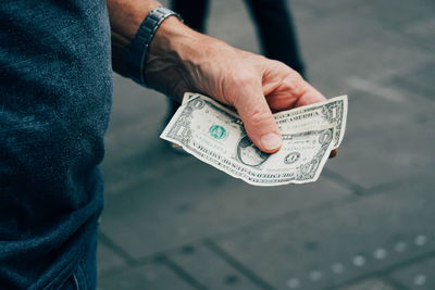 Cropped image of man holding paper currency on street