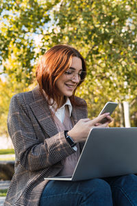 Smiling businesswoman using laptop while sitting at park