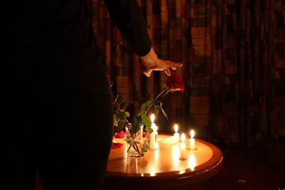 Midsection of woman touching rose in darkroom