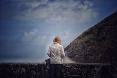 Rear view of woman standing on mountain against sky