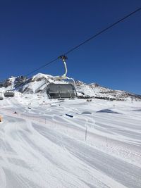 Overhead cable car in snow covered mountains against clear blue sky