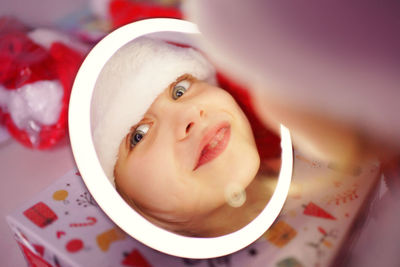 Reflection in the mirror of a christmas caucasian girl in santa's cap.