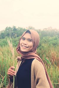Portrait of smiling young woman standing on field