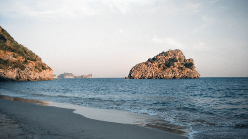 Rock formation on beach against sky