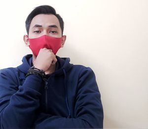 Portrait of young man covering face against white background