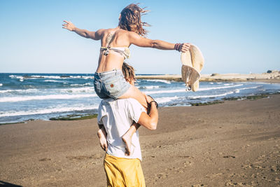 Rear view of man standing at beach against sky