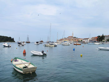 Sailboats moored in sea against sky