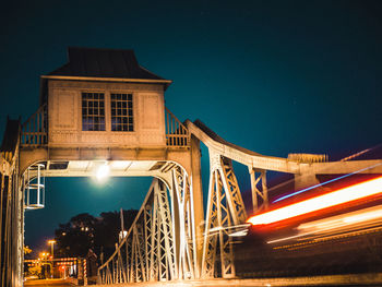 Light trails on bridge against sky at night