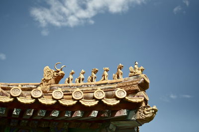 Low angle view of sculpture on building against sky