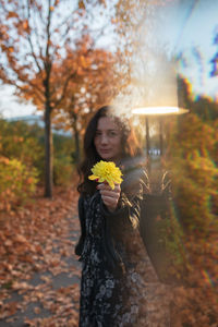 Digital composite portrait of woman holding flower during autumn