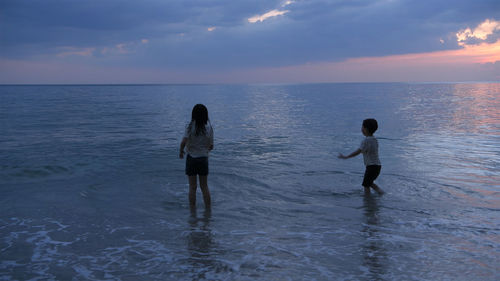 People on sea shore against sky during sunset