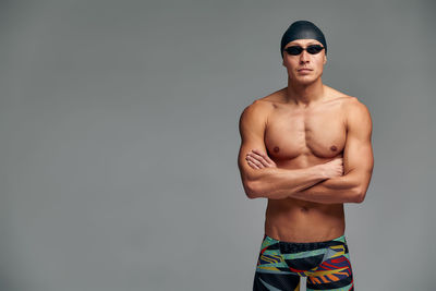 Portrait of shirtless man standing against black background