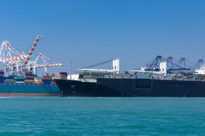 Commercial dock by sea against blue sky