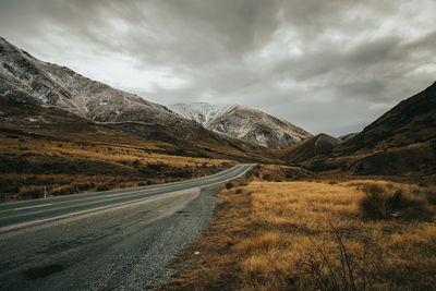 Road by mountains against sky