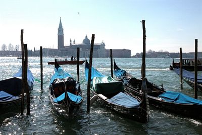 Boats moored in sea with city in background