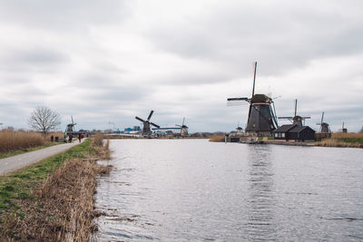 Traditional windmill by canal against sky