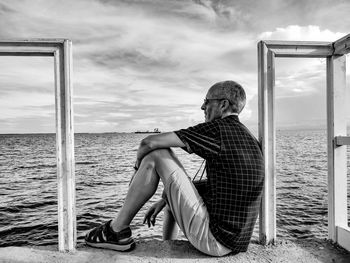 Rear view of man looking at sea against sky