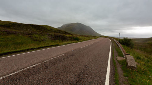 Empty road by mountain against sky