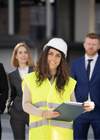 Portrait of smiling young woman using mobile phone while standing outdoors