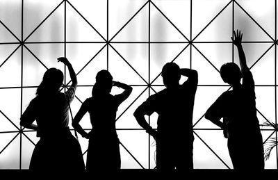 Silhouette friends standing in front of patterned glass