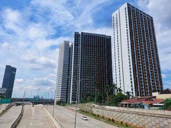 Modern buildings by road against sky in city