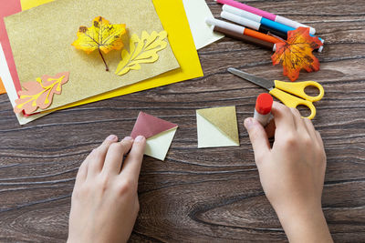 High angle view of woman holding paper on table