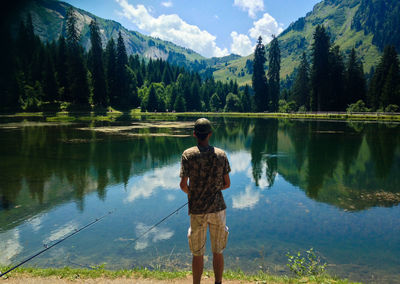 Rear view of man standing by lake