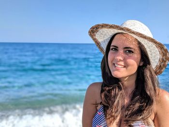 Portrait of smiling woman in hat at beach against sky