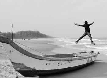 Man jumping in sea against sky