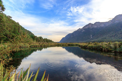 Scenic view of lake by mountains against sky