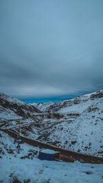 Snow covered landscape against sky with workers in the mountains. 