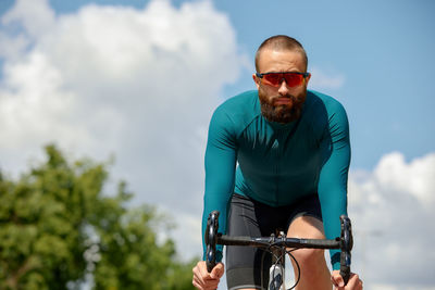 Young man riding bicycle against sky