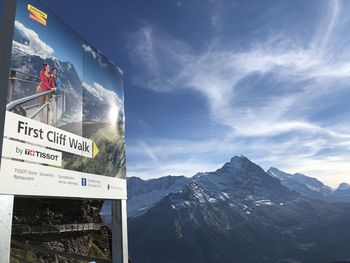 Information sign on snowcapped mountains against sky